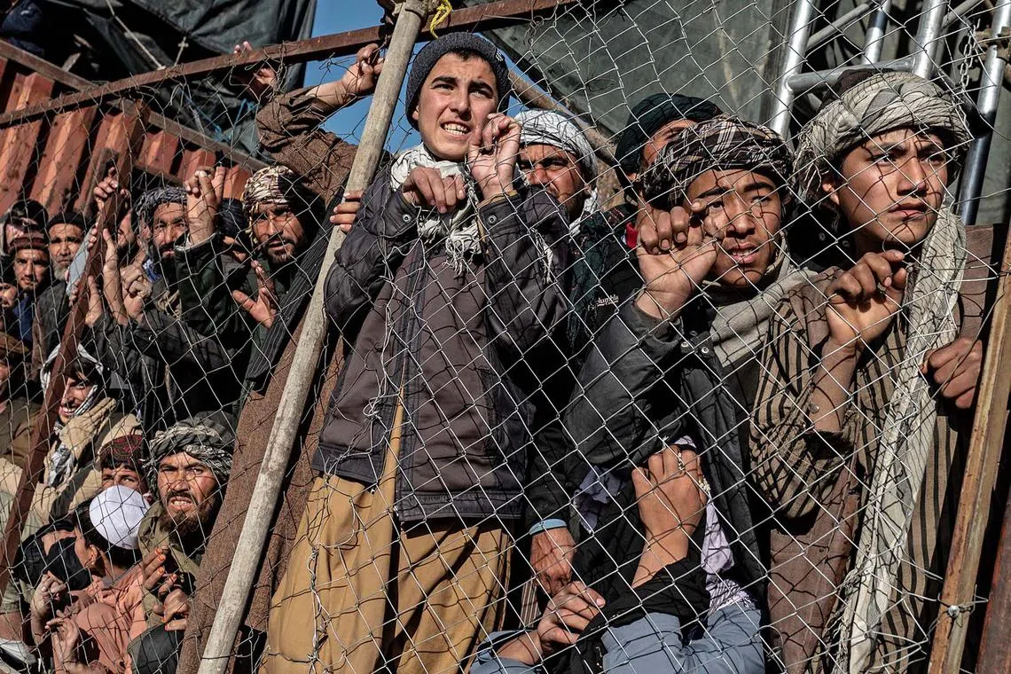 Spectators watching through a mesh fence as Afghan horsemen from Baghlan and Sar-e Pol teams compete with each other during the fifth Buzkashi League in Kabul on Dec 28, 2023. 