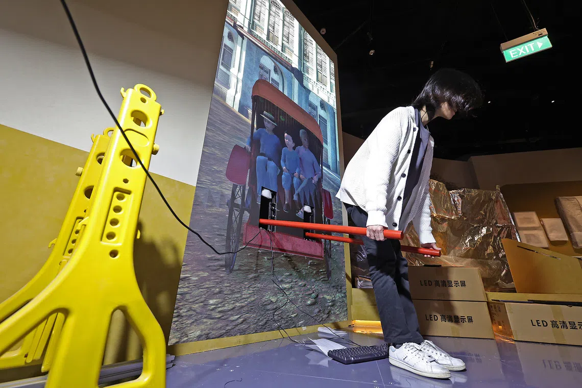 A representative from creative technology studio CraveFX testing the "phygital" rickshaw installation in the Colonial City section of the gallery on Sept 8, 2026. This interactive installation allows visitors to take on the role of a rickshaw puller, and experience the daily grind of Singapore’s early street workers. The interactive scales the rickshaw's weight down from 50kg to 30kg for visitor safety and accessibility.
