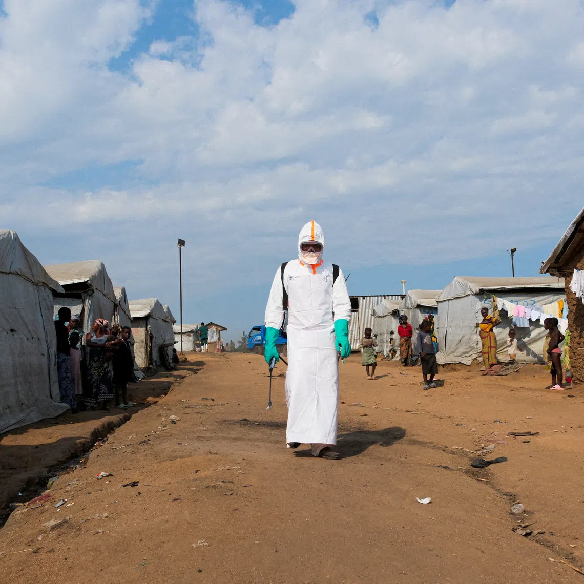 FILE PHOTO: Displaced people watch a health worker in full personal protective equipment (PPE) preparing to disinfect the area during the burial of suspected Ebola victims at the Kigonze displaced persons camp in Bunia, eastern Democratic Republic of Congo, on June 18, 2026, one month after the outbreak was declared. REUTERS/Gradel Muyisa Mumbere/File Photo