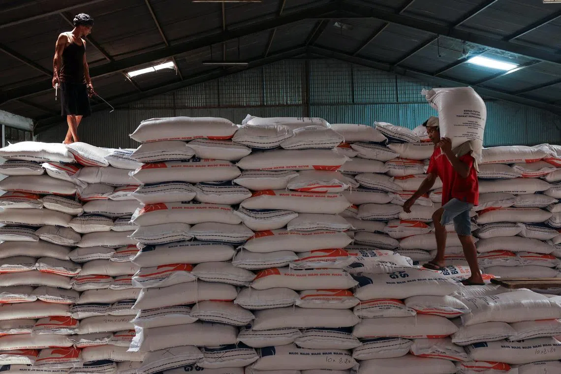 A worker stands on a pile of rice sacks as the other worker carries a sack of rice at the warehouse in Jakarta, Indonesia, February 13, 2024. REUTERS/Ajeng Dinar Ulfiana/File Photo
