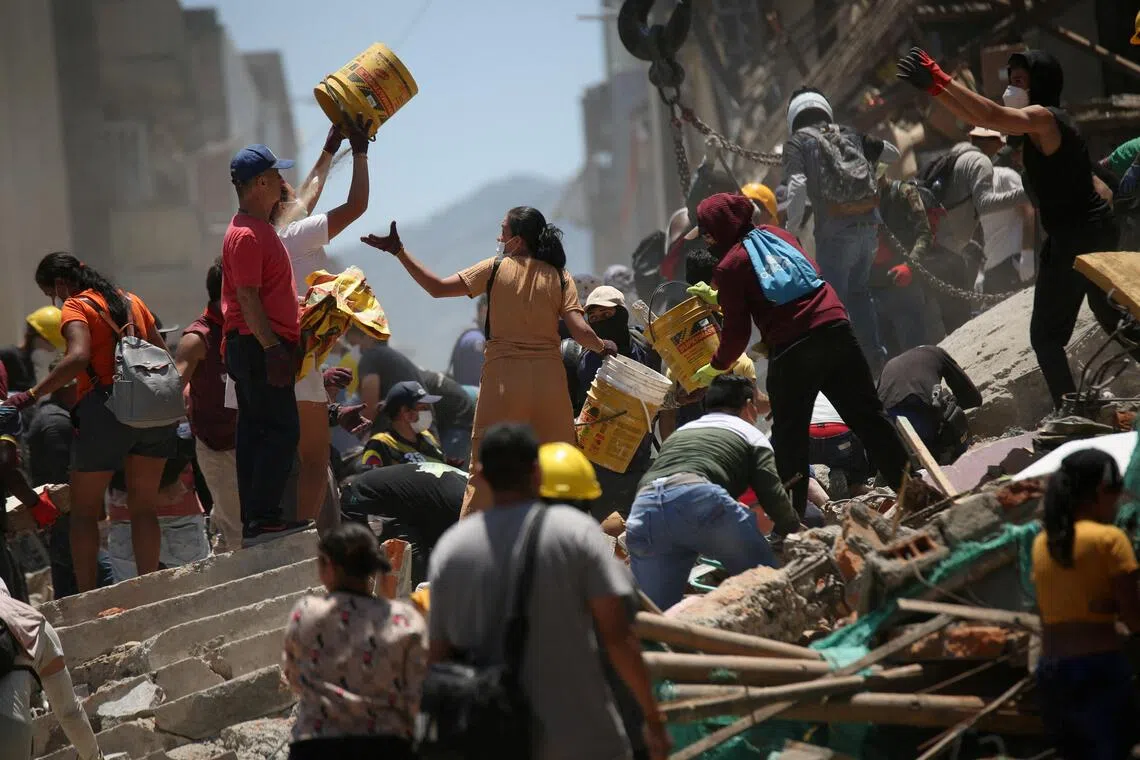 People shifting rubble at the site of a damaged building in Pereira, Colombia, on Aug 11.