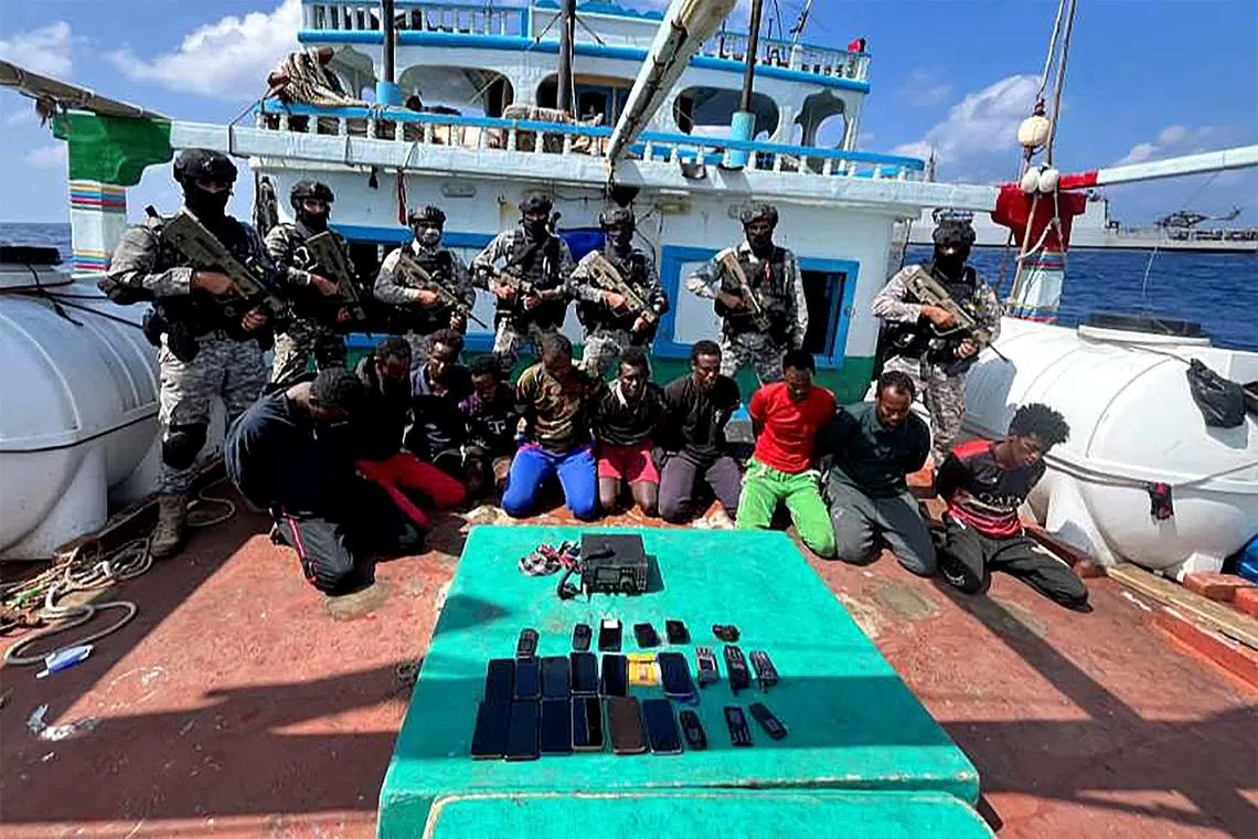 Indian commandos stand guard with a group of detained pirates after the Indian Navy freed an Iranian fishing vessel hijacked by Somali pirates.