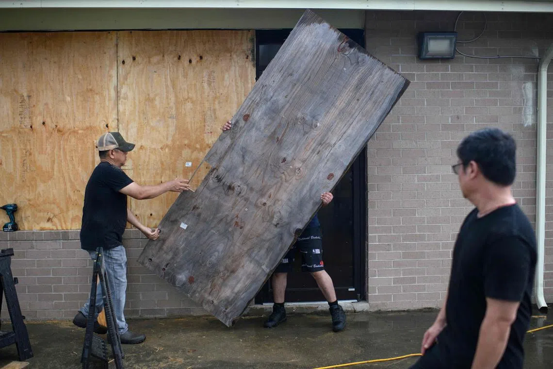 A group of men board up a restaurant in Port Lavaca, Texas, on July 7, 2024, as they prepare for the arrival of Hurricane Beryl. 