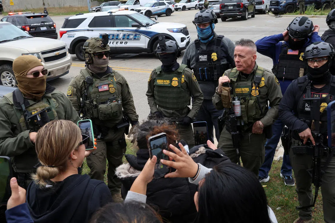 People use their phones to record as they argue with federal agents at an intersection in the Cicero neighborhood during an immigration raid, after U.S. President Donald Trump ordered increased federal law enforcement presence to assist in crime prevention, in Chicago, Illinois, U.S., October 22, 2025. REUTERS/Jim Vondruska