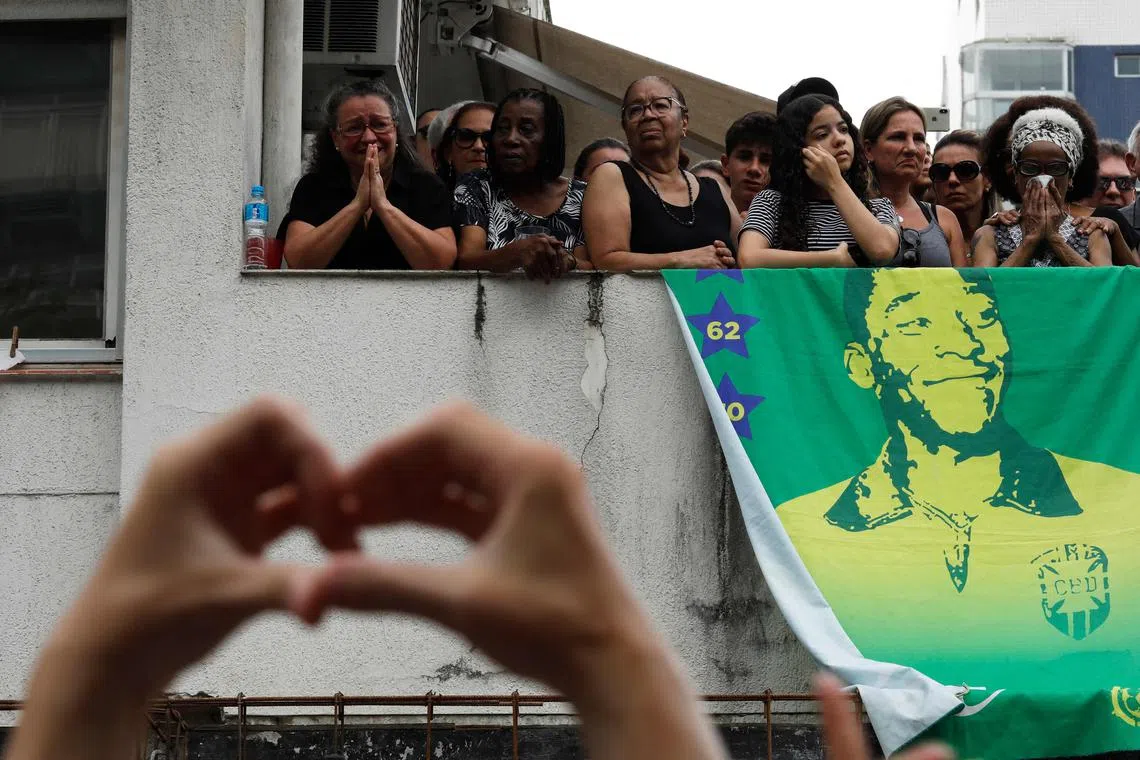 Fans of the late Brazilian football star Pele observe from the house of Pele's mother as Pele's casket is transported to its final resting place, Santos, Brazil, Jan 3, 2023. 