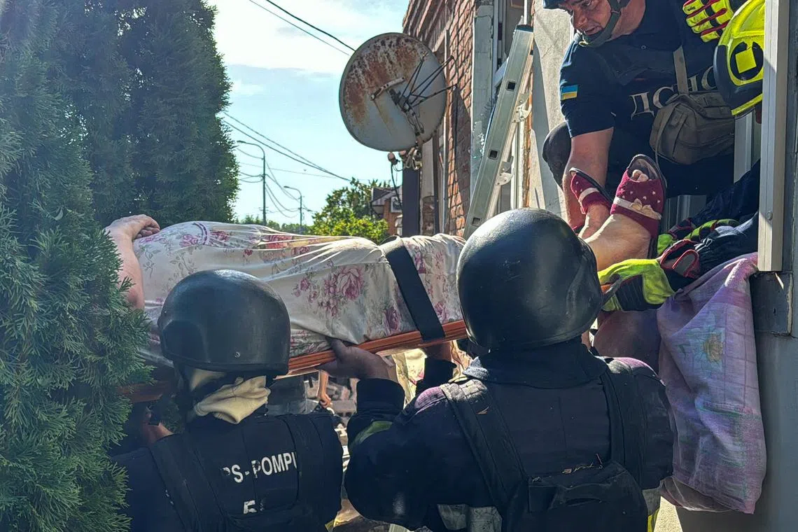 Emergency workers carrying a woman from a residential building in Kharkiv that was damaged by a Russian air strike, on July 3.