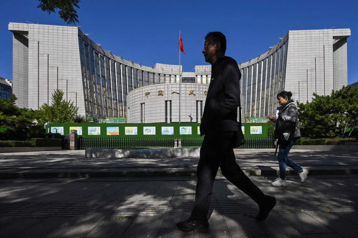 People walk past the People’s Bank of China, the country’s central bank, in Beijing on October 19, 2024. (Photo by ADEK BERRY / AFP)