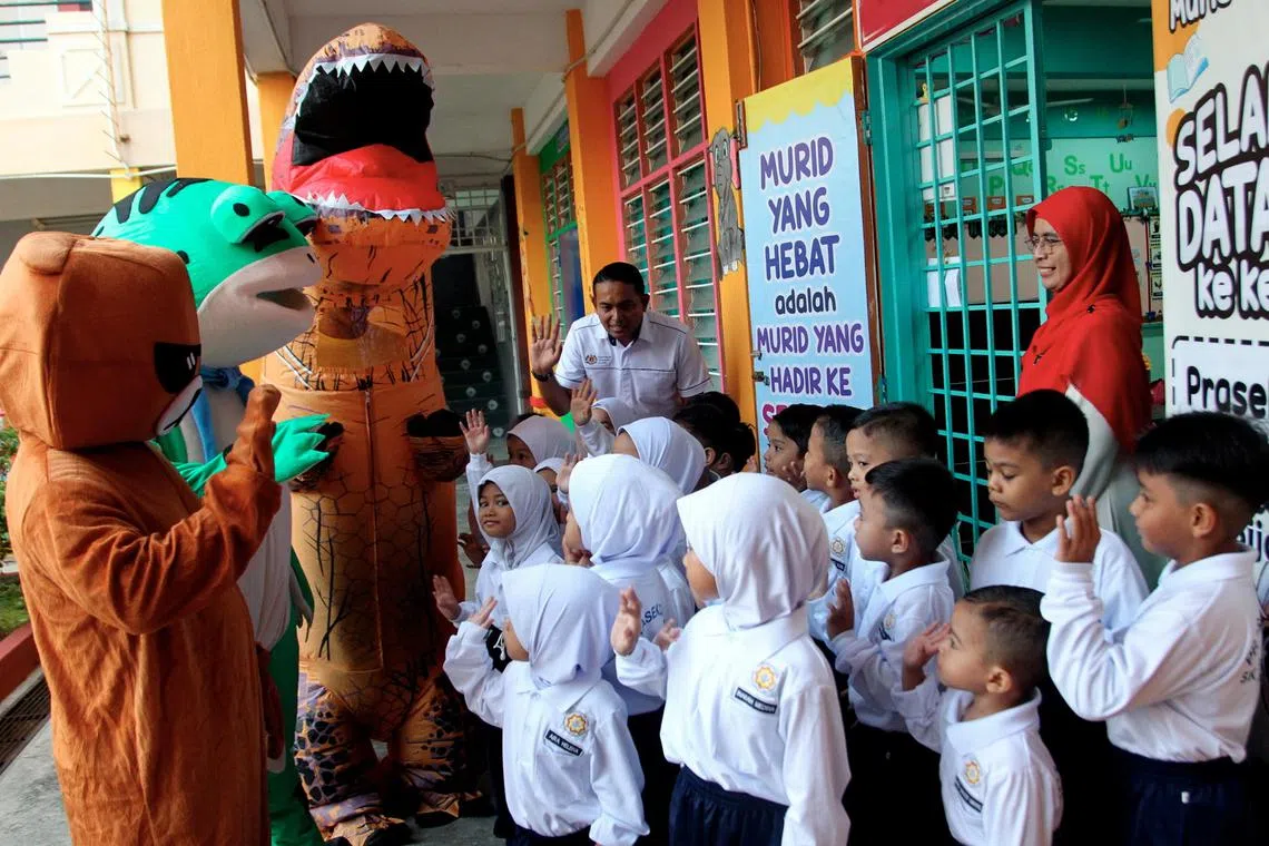 Children being greeted by bear,  frog and T-Rex mascots during the first day of school at Sekolah Tasik Damai in Ipoh, Perak on March 11.
