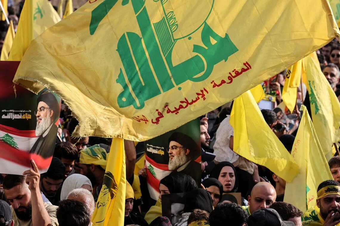 Hezbollah supporters raise the party's yellow flags and pictures of its slain leader in Beirut's seaside Raouche area, on Sept 25, 2025.