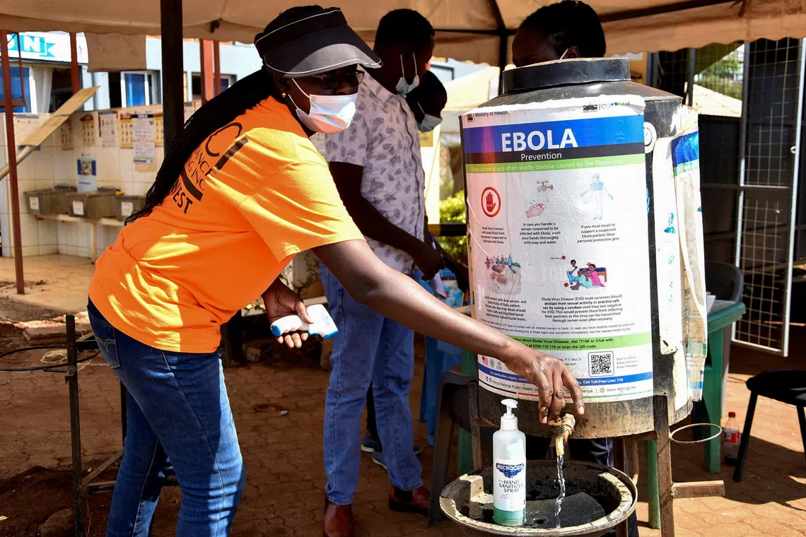 A medical worker controls the sanitisation point for travellers entering the Kenya immigration services from Uganda at a border post in Busia, Kenya.
