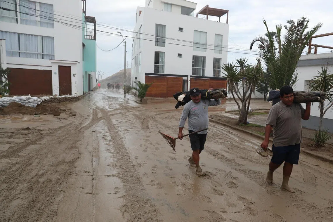 People walk in a street full of mud following Cyclone Yaku in Lima, Peru, March 15, 2023. REUTERS/Sebastian Castaneda
