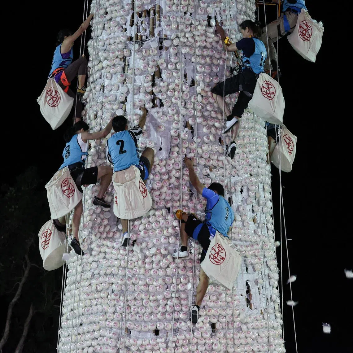 Participants competing to climb a 14-metre bun tower during the bun-snatching competition at the Cheung Chau Bun Festival in Hong Kong on May 25, 2026.