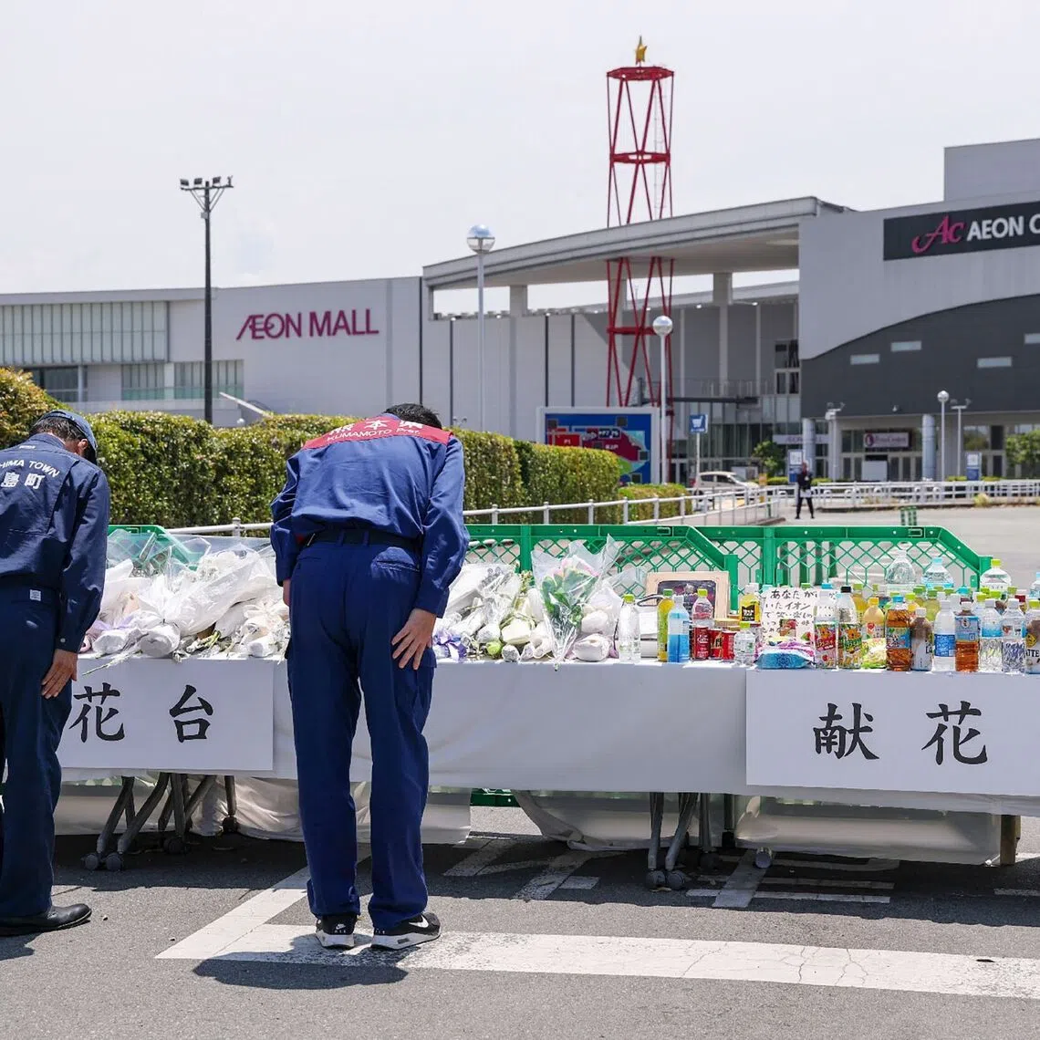 Takashi Kimura (right), governor of Kumamoto prefecture, bows as he lays flowers outside the damaged Aeon Mall Kumamoto in Kashima, Kumamoto Prefecture, on Aug 11.