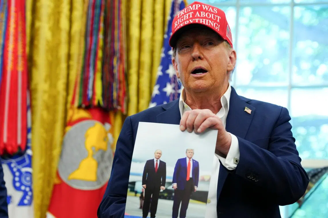 US President Donald Trump holding a photo of himself with Russian President Vladimir Putin in Alaska, while speaking in the Oval Office on Aug 22.