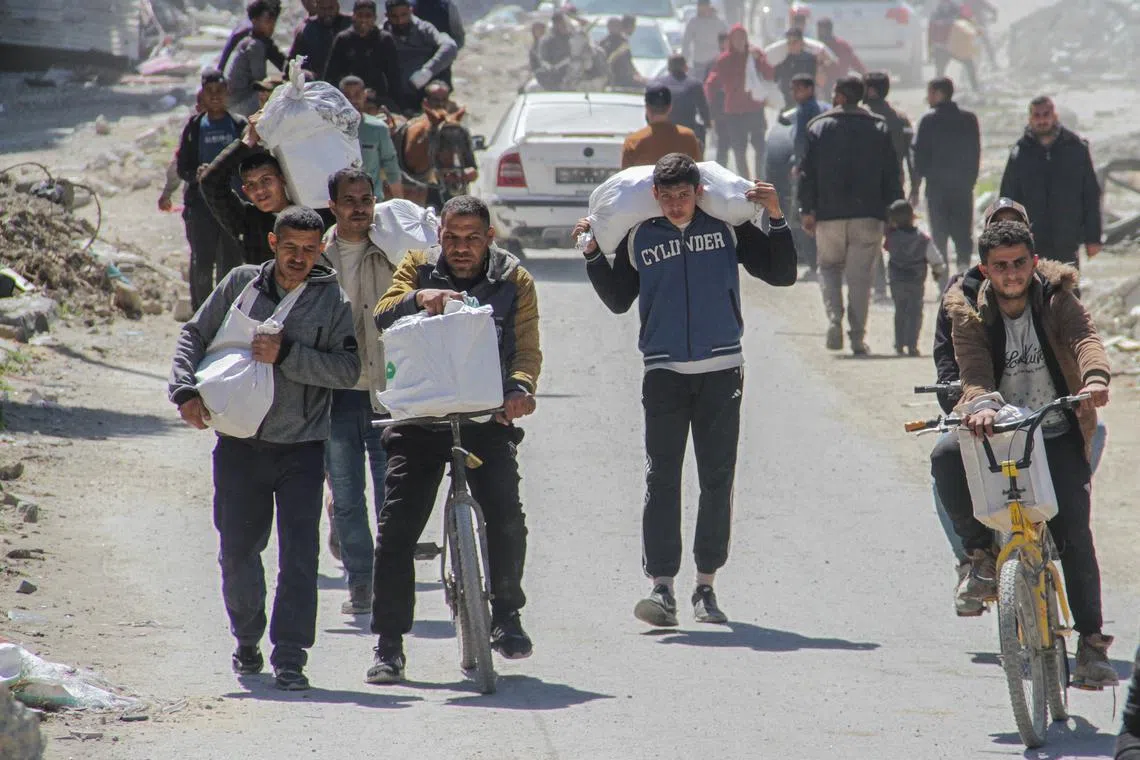 FILE PHOTO: Palestinians carry aid unloaded from a truck, amid the ongoing conflict between Israel and Hamas, in Gaza City, March 23, 2024. REUTERS/Mahmoud Issa/File Photo