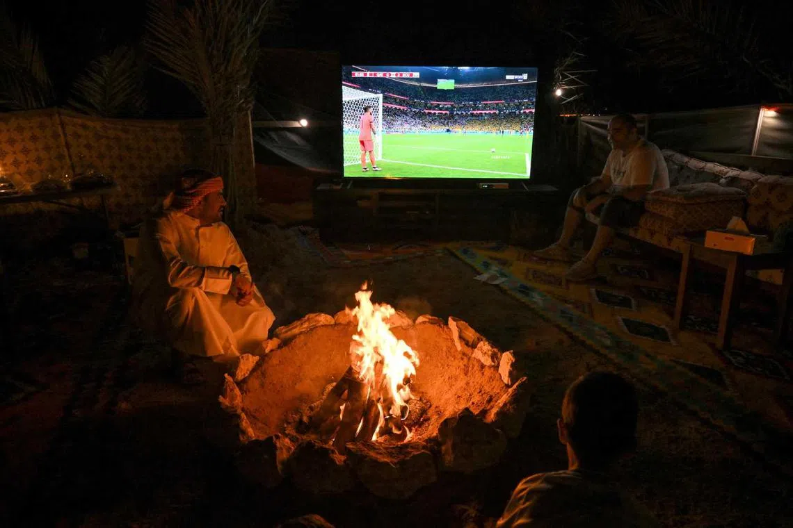 People watch on TV the Qatar 2022 World Cup football tournament opening Group A match between Qatar and Ecuador, at a desert camp north of Doha, on Nov 20, 2022. 