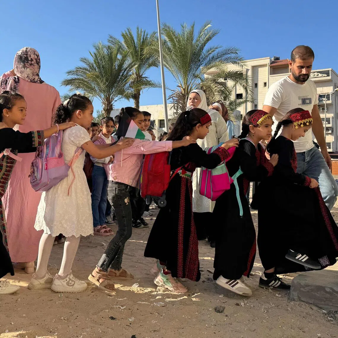 Displaced children from the Gaza Strip, stand in line as they attend a Palestinian school in the Egyptian city of El-Arish, near the border with the Gaza Strip, on October 1, 2026. On Egypt’s Sinai Peninsula, Palestinian teacher Hadeel Zourob welcomes dozens of pupils from Gaza to the only Palestinian school in the region – a school she set up for these children displaced by the war. Hadeel Zourob arrived in April 2024, six months after the war began. Together with other teachers, she began teaching a small group of children in a rented building. (Photo by Amr AHMED / AFP)