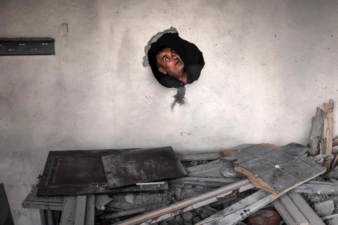 A man looking through a hole amidst the rubble of a building hit by an Israeli air strike in Deir al-Balah in the centre of the Gaza Strip, on May 13.