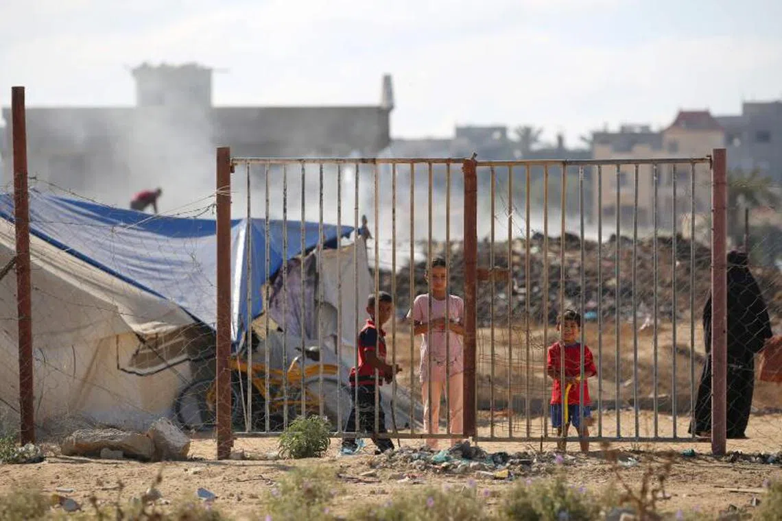 Children stand next to tents at a camp housing displaced Palestinians in the Al-Bureij camp in the central Gaza Strip.