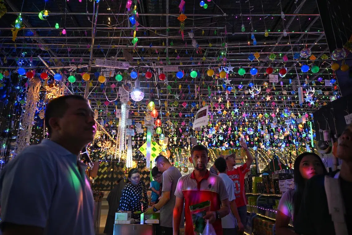 People at a stall selling decorative lights in Geylang Serai Ramadan bazaar. People shopping at Geylang Serai Ramadan bazaar on Apr 2, 2024, in preparation of Hari Raya, which falls on Apr 10, 2024.