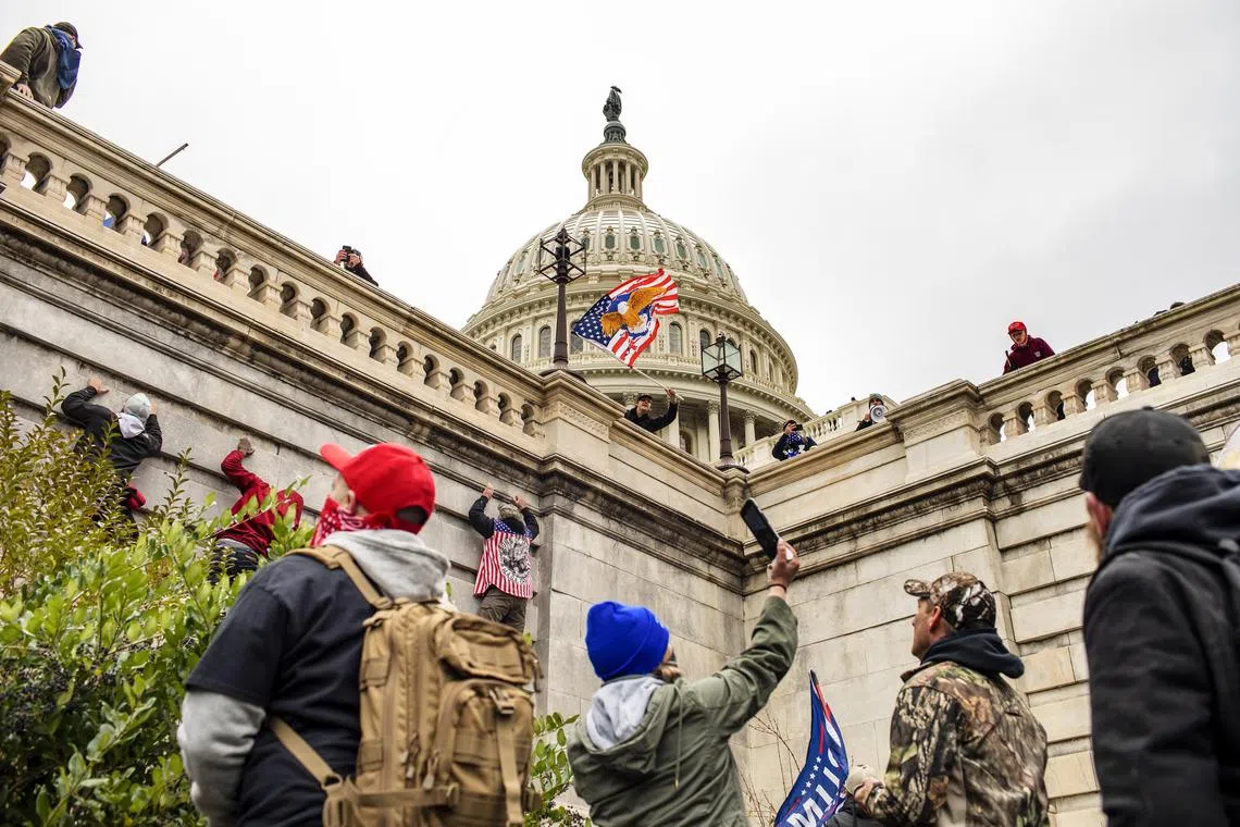 A mob of supporters of former President Donald Trump climb the walls outside the Capitol in Washington on Jan 6, 2021. 