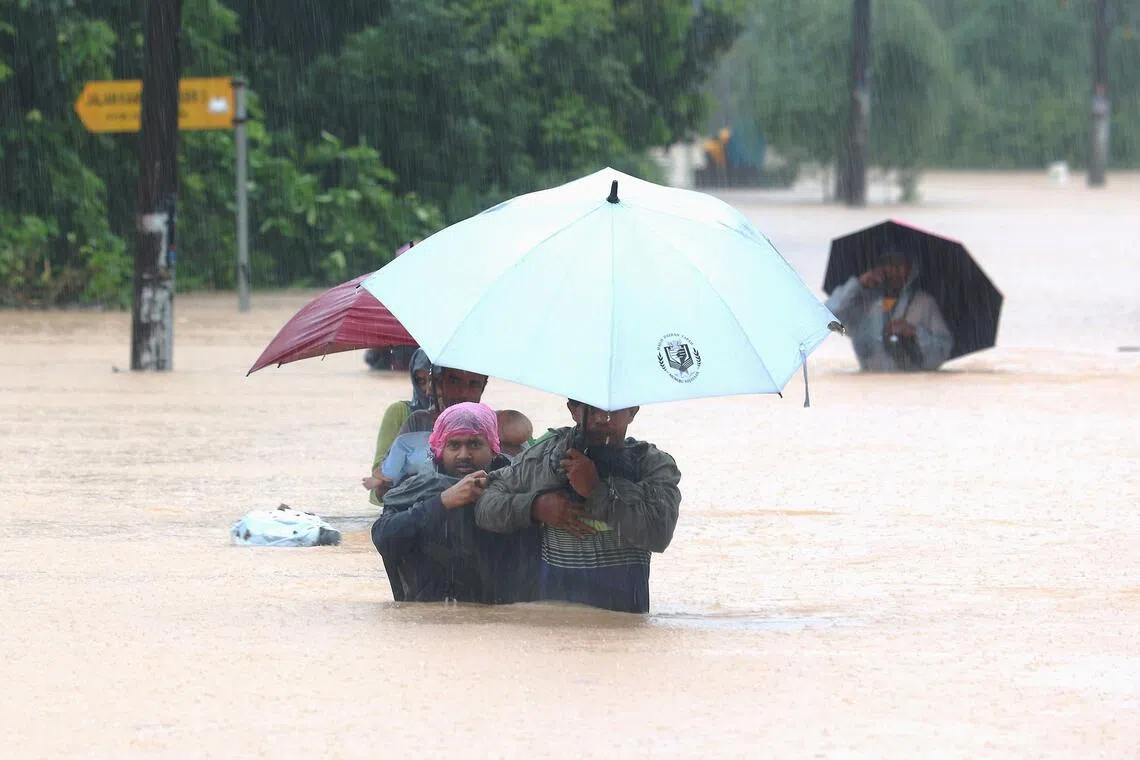 fdflood20 - Line of hope: a man leading his friends and family out of their village at Kampung Pasir Tebrau, Johor Baru. 

Credit: The Star