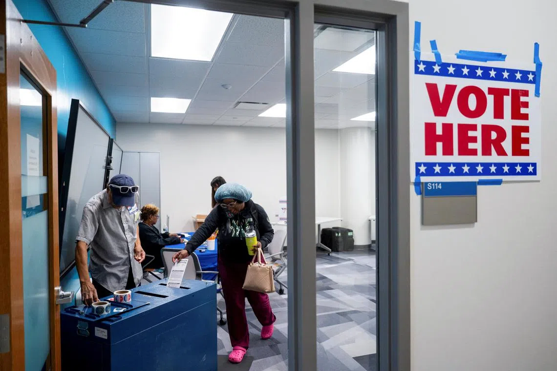 A woman puts her ballot in a ballot box on the second day of early voting in Wisconsin at the Milwaukee Area Technical College in Milwaukee, Wisconsin, U.S. October 23, 2024. REUTERS/Vincent Alban
