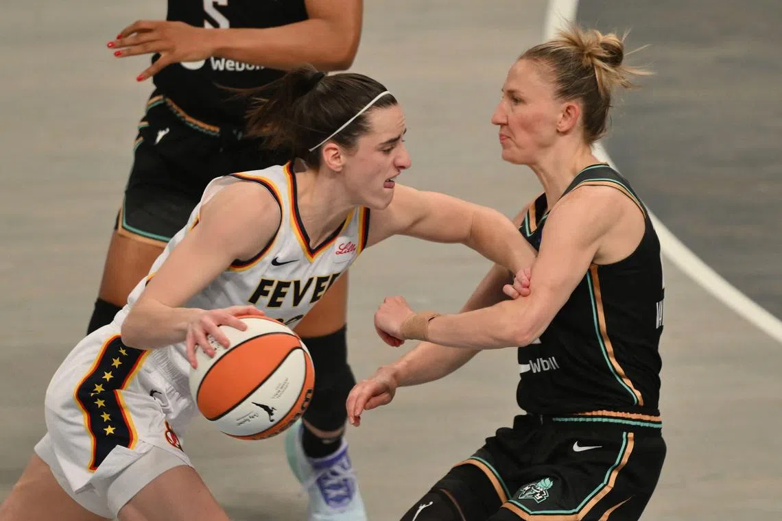 Indiana Fever's Caitlin Clark dribbles the ball while guarded by New York Liberty's Courtney Vandersloot during a WNBA game on May 18, 2024.