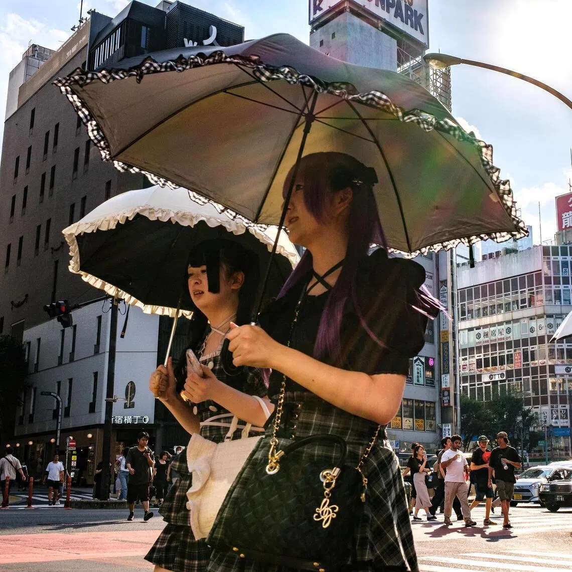 Pedestrians holding umbrellas walk on a hot day amid a heatwave in Tokyo's Shinjuku district on August 30, 2025. (Photo by Philip FONG / AFP)