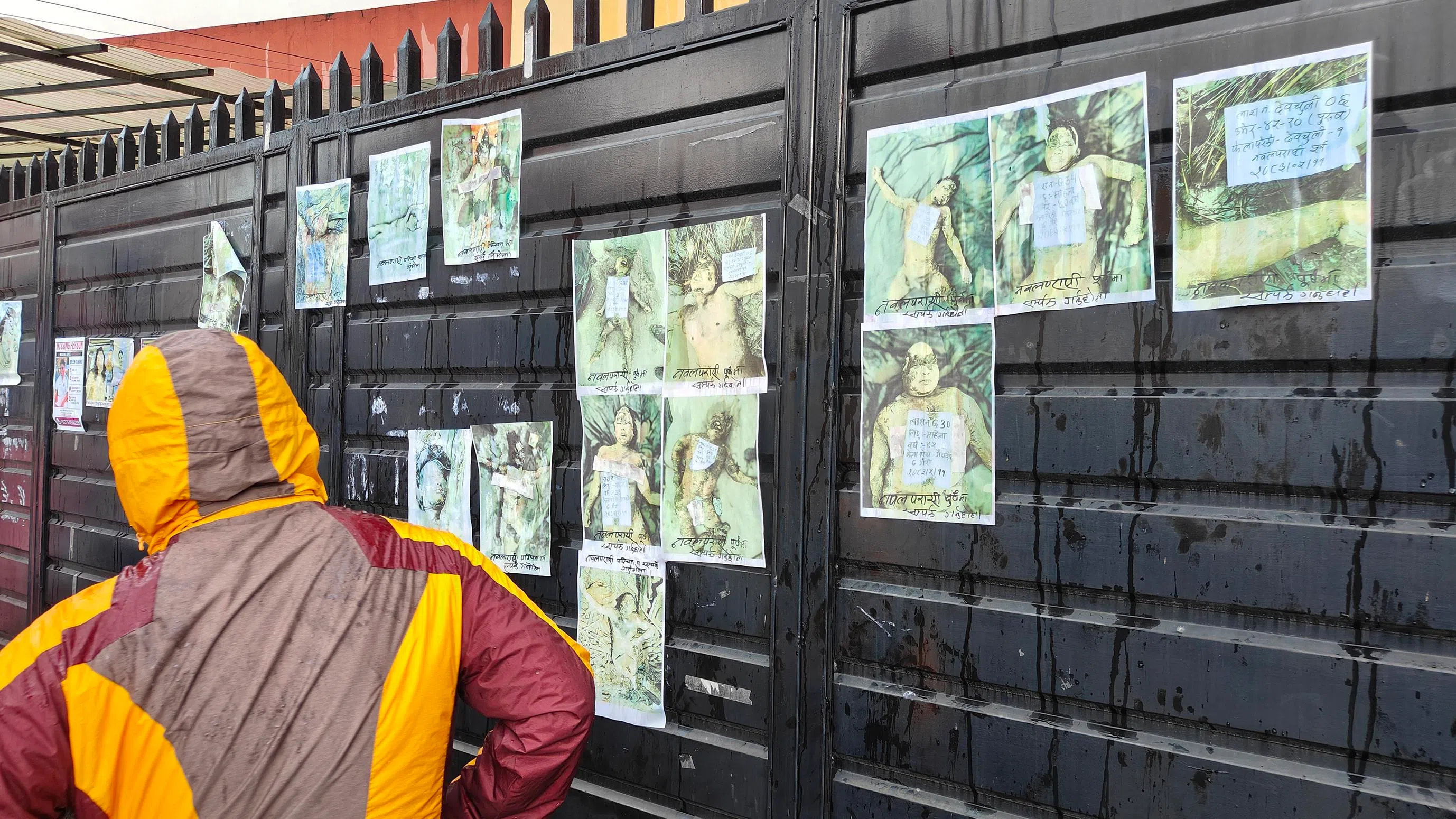 A man looks at photos of unidentified corpses pasted on a gate outside the Tribhuvan University Teaching Hospital in Kathmandu on Aug 28.