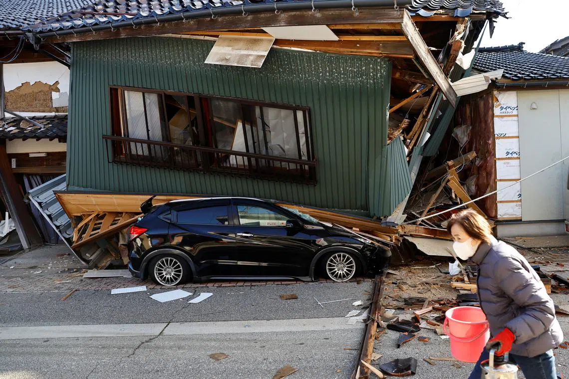 A resident walking past a collapsed house, caused by an earthquake, in Nanao, Ishikawa prefecture, Japan, on Jan 2, 2024.
