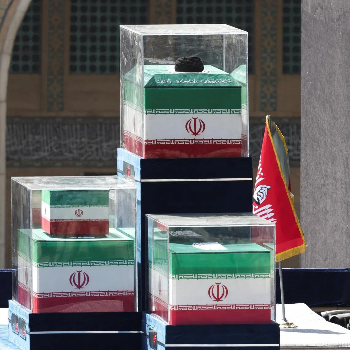 A turban is placed over the coffin of Iran’s late Supreme Leader Ayatollah Ali Khamenei, near the coffins of Khamenei’s family members in the colours of Iranian flags on the stage, as people gather for a public farewell ceremony.