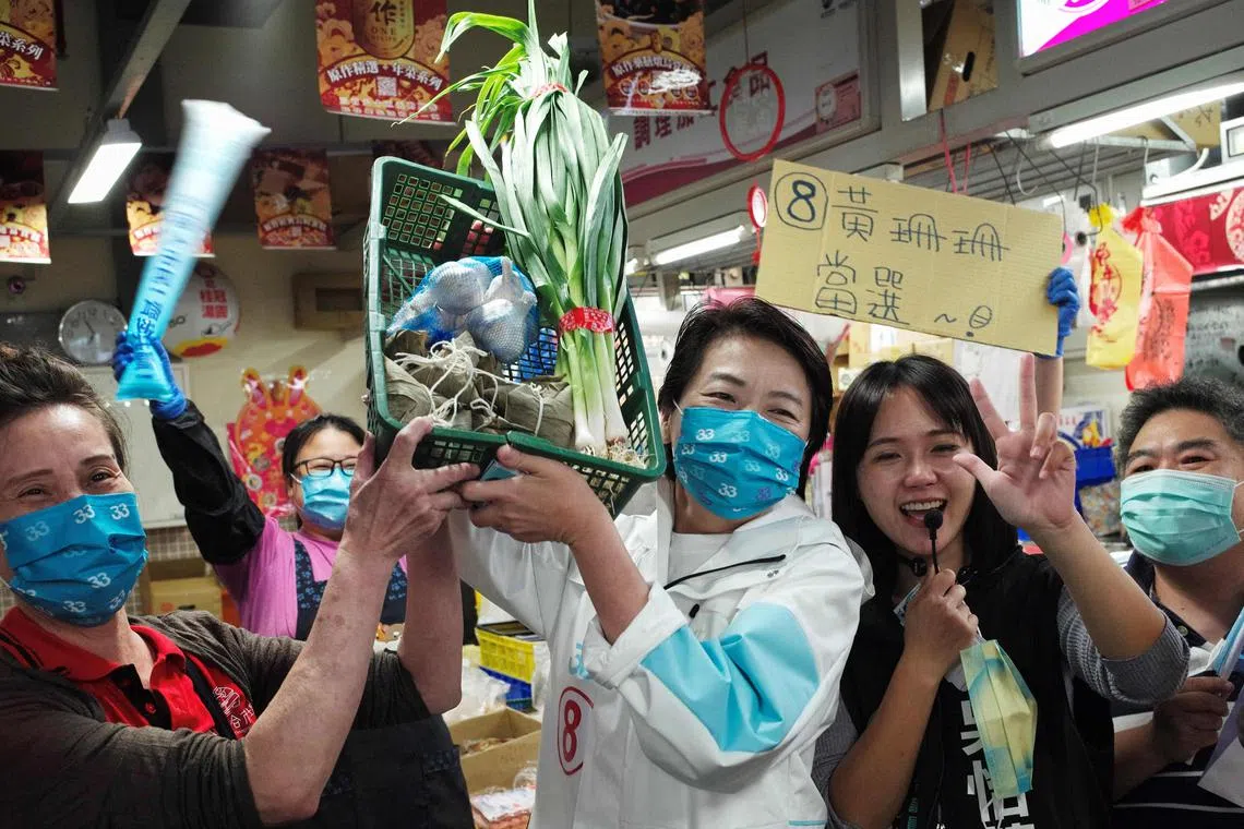 Independent Taipei mayoral candidate Huang Shan-shan (C) posing with a basket of "lucky vegetables" received by supporters during an election campaign at the Huannan Market in Taipei on Nov 23, 2022.