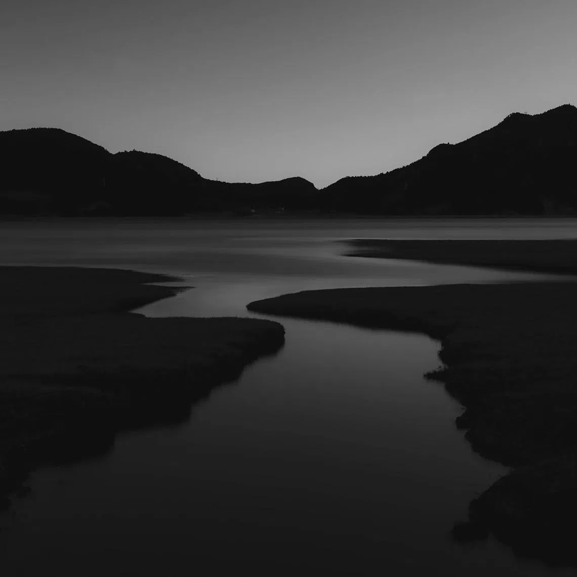 During a solo hike in Wenhai, China, the photographer came across a serene, narrow stream meandering through dark grasslands, flowing towards a vast, still lake in the distance. The image was edited with muted tones and high contrast to evoke the look of a pencil sketch, capturing the solitude and tranquillity of the journey. Photo: © Ng Guang Ze, Singapore, Winner, National Awards, Sony World Photography Awards 2025