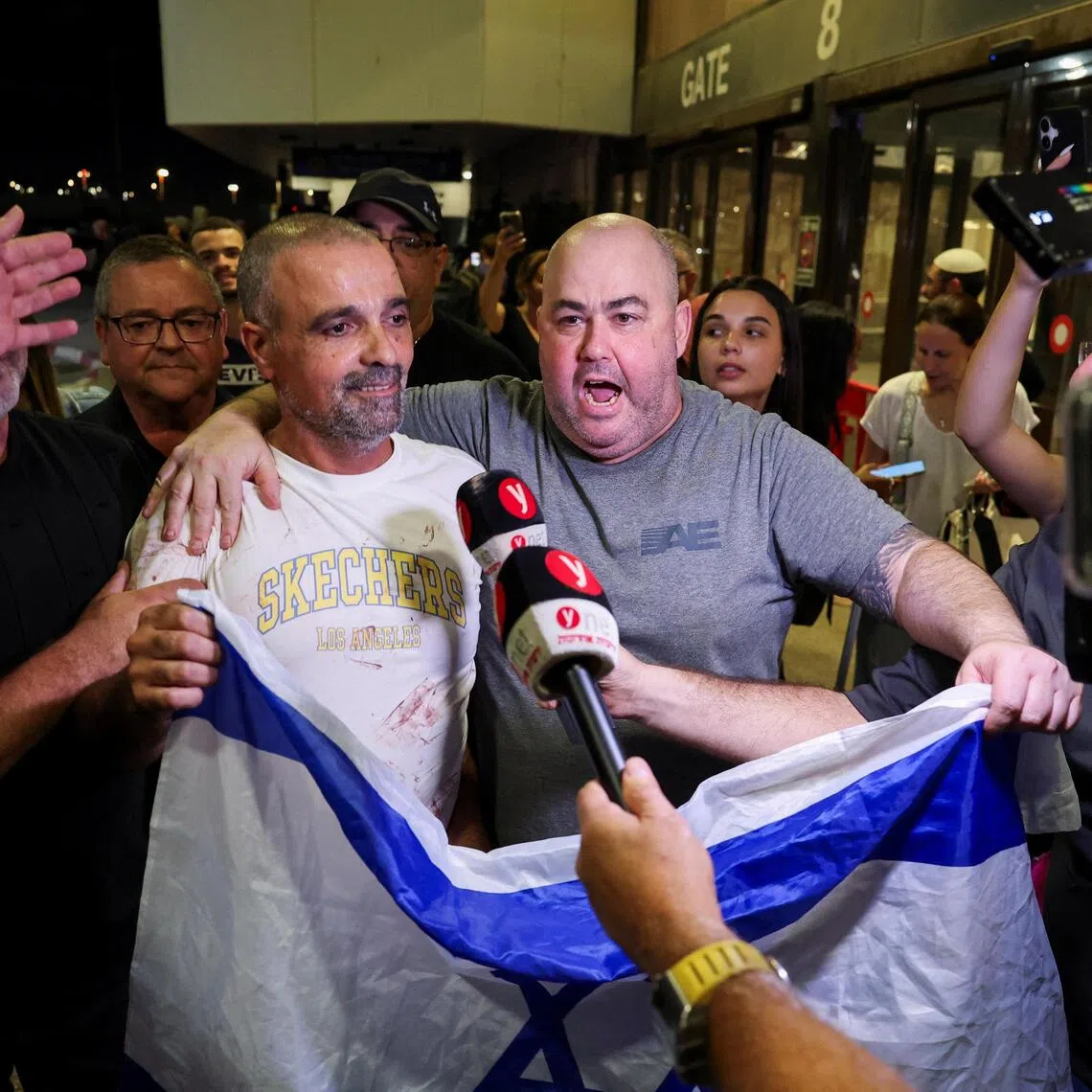 Yaniv Hayun (left) - one of the men who helped incapacitate the attacker on a flydubai aircraft from the UAE to Israel - holding an Israeli flag as he returns to Israel on Sept 30.