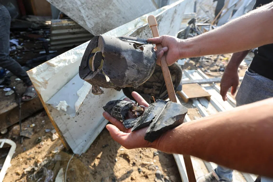 A person holding the remains of a rocket at the site of an Israeli strike on tents housing displaced people, in the central Gaza Strip, on Nov 9.