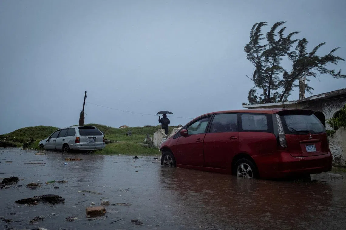 FILE PHOTO: A man looks at breaking waves in the Caribbean Terrace neighborhood as Hurricane Beryl approaches, in Kingston, Jamaica, July 3, 2024. REUTERS/Marco Bello/File Photo