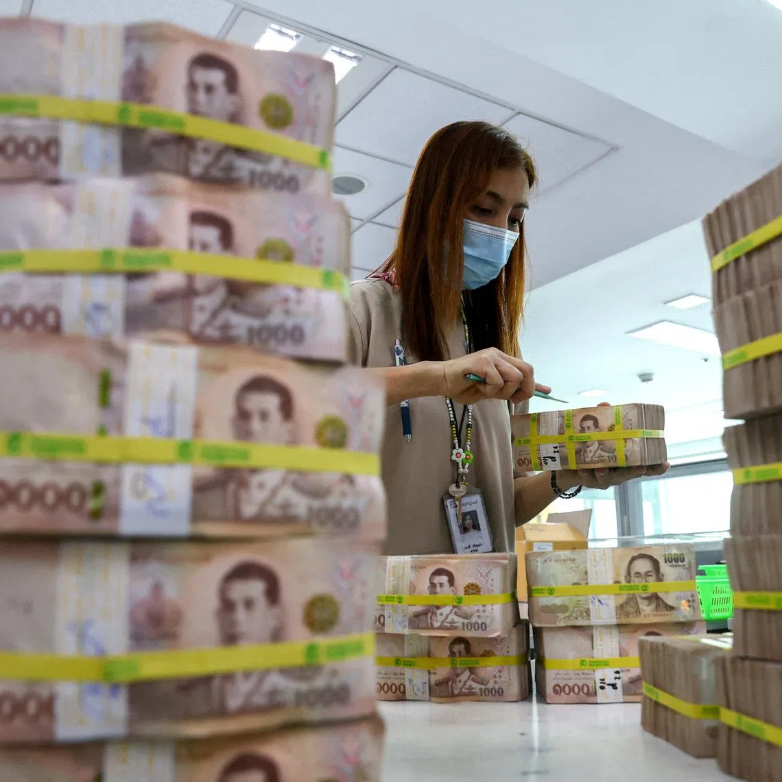 FILE PHOTO: A bank employee gathers Thai baht notes at a Kasikornbank in Bangkok, Thailand, January 26, 2023. REUTERS/Athit Perawongmetha/File Photo
