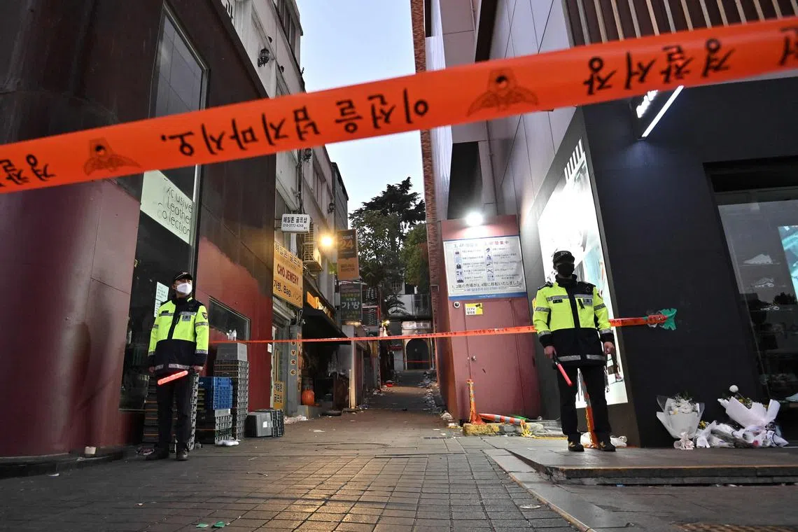 TOPSHOT - Police stand guard at the cordoned scene of the deadly Halloween crowd surge in the district of Itaewon in Seoul on November 1, 2022. (Photo by Jung Yeon-je / AFP)