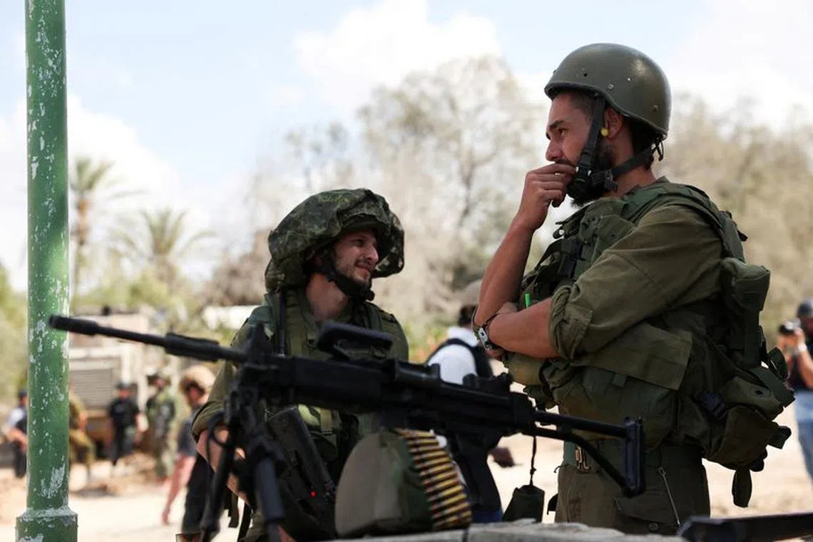 FILE PHOTO: Members of the Israeli Defense Forces stand guard, following a deadly infiltration by Hamas gunmen from the Gaza Strip, in Kibbutz Kfar Aza, southern Israel, October 18, 2023. REUTERS/Violeta Santos Moura/File Photo