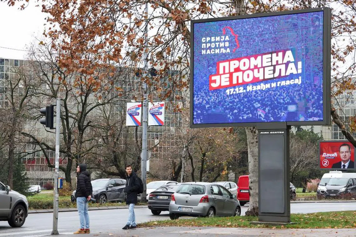 FILE PHOTO: People stand next to a pre-election billboard of the opposition coalition 'Serbia Against Violence'  in Belgrade, Serbia, December 14, 2023. REUTERS/Zorana Jevtic/File Photo