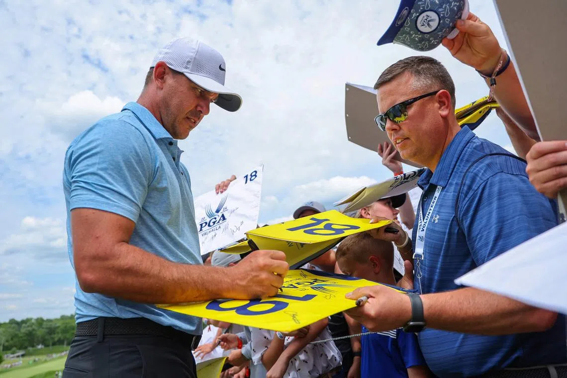 Brooks Koepka of the United States signs his autograph for fans during a practice round prior to the 2024 PGA Championship at Valhalla Golf Club.