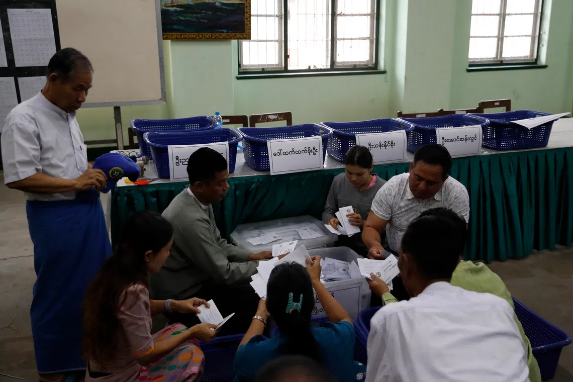 Electoral officers count early voting ballots at a polling station in Yangon, Myanmar, on Dec 26.