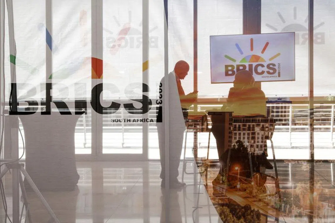 Delegates interact next to the logos of the BRICS summit during the 2023 BRICS Summit at the Sandton Convention Centre in Johannesburg, South Africa on August 23, 2023. GIANLUIGI GUERCIA/Pool via REUTERS