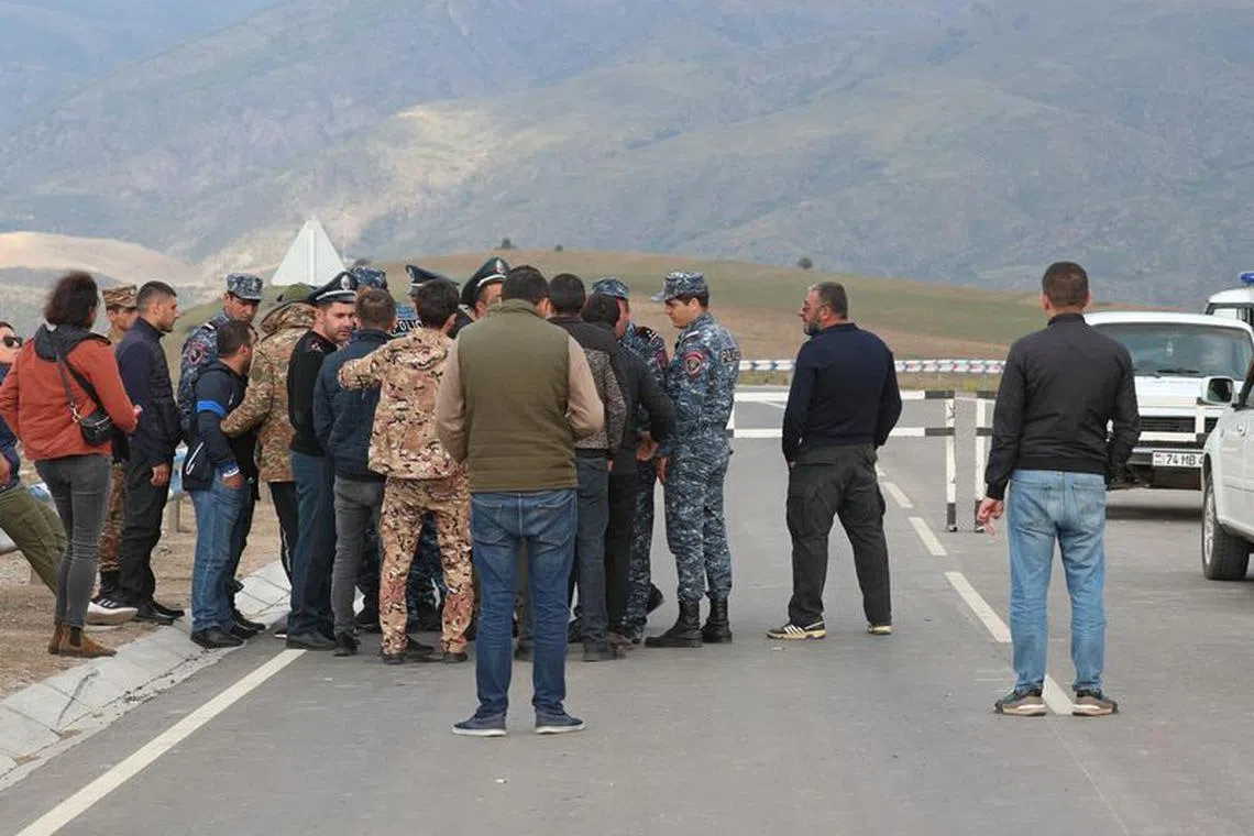 People gather near the Armenian border guard post on the road leading from Armenia to Azerbaijan's Nagorno-Karabakh region, near the village of Kornidzor, Armenia September 21, 2023. REUTERS/Irakli Gedenidze