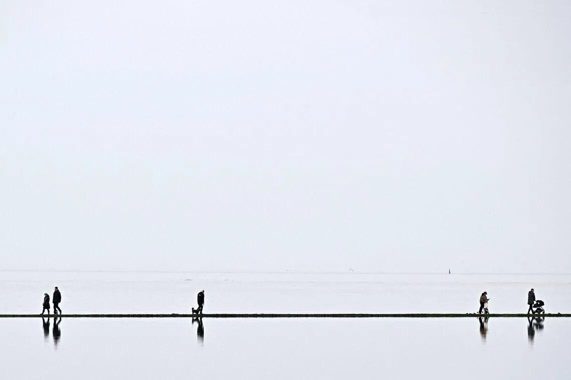 People walking around the Marine Lake at West Kirkby in north west England on March 23.
