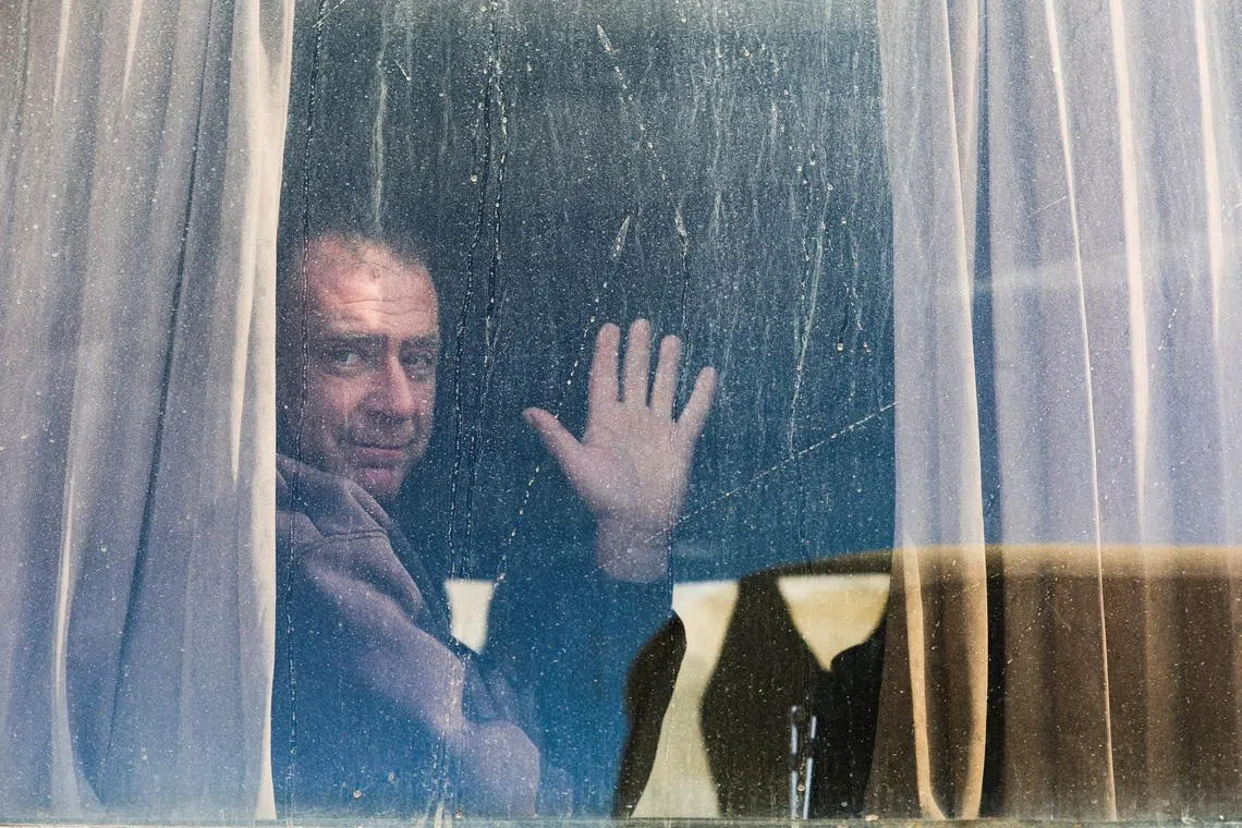 A Palestinian man waves from a window as war-wounded people and patients, accompanied by relatives, get ready to leave Gaza for treatment abroad through the Rafah border crossing between Gaza and Egypt, after it was opened by Israel on Monday for a limited number of people, in Khan Younis in the southern Gaza Strip, February 3, 2026. 