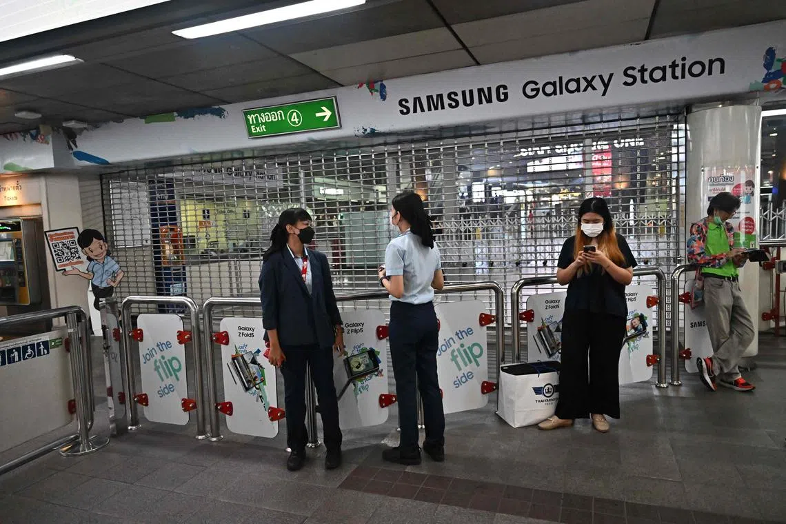 Employees and commuters standing at a closed exit of a BTS train station near Siam Paragon mall in downtown Bangkok on October 3, 2023. 