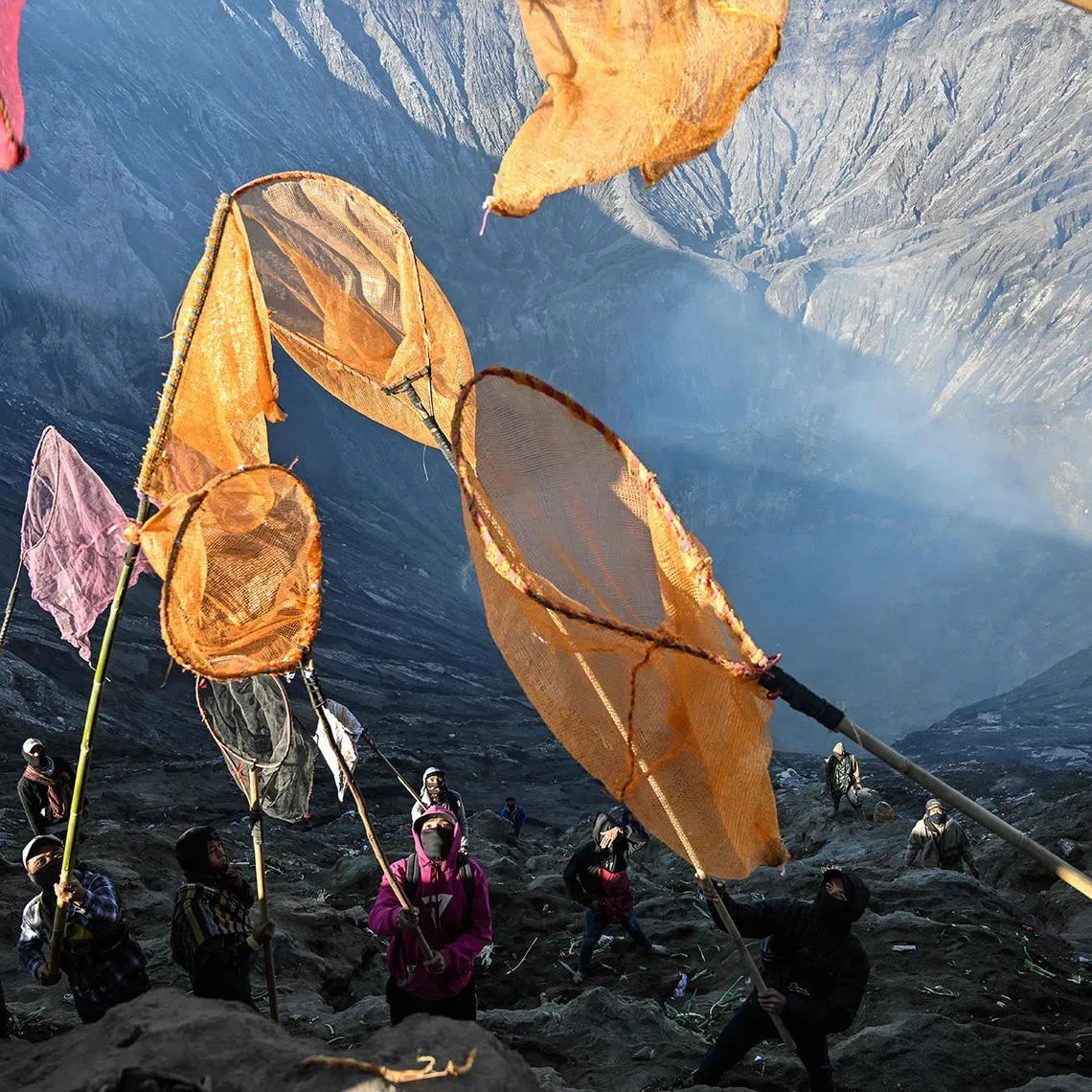 Villagers catch offerings thrown into Mount Bromo’s crater by Tengger Hindu devotees during the Yadnya Kasada festival in East Java, Indonesia. 