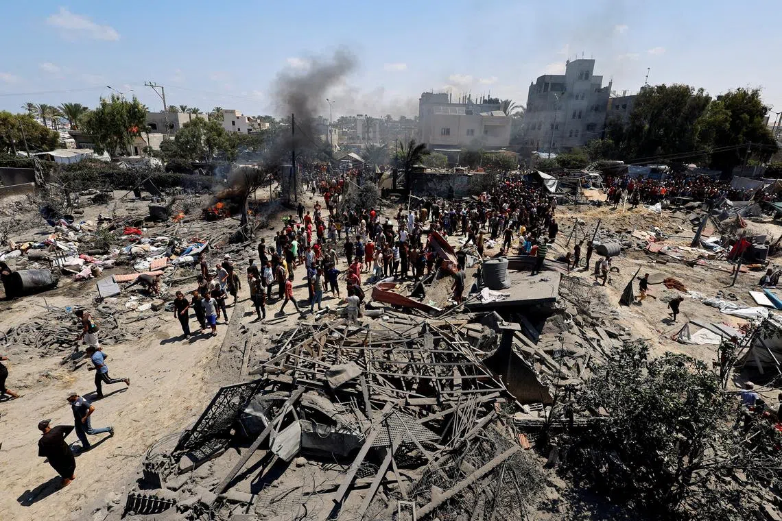 FILE PHOTO: Palestinians gather near damage, following what Palestinians say was an Israeli strike at a tent camp in Al-Mawasi area, amid Israel-Hamas conflict, in Khan Younis in the southern Gaza Strip July 13, 2024. REUTERS/Mohammed Salem/File Photo
